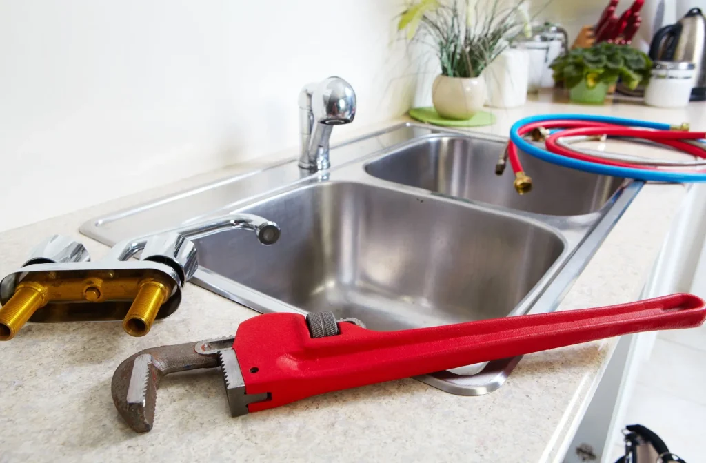 Pipe wrench, cold and hot water hoses and faucet on kitchen countertop